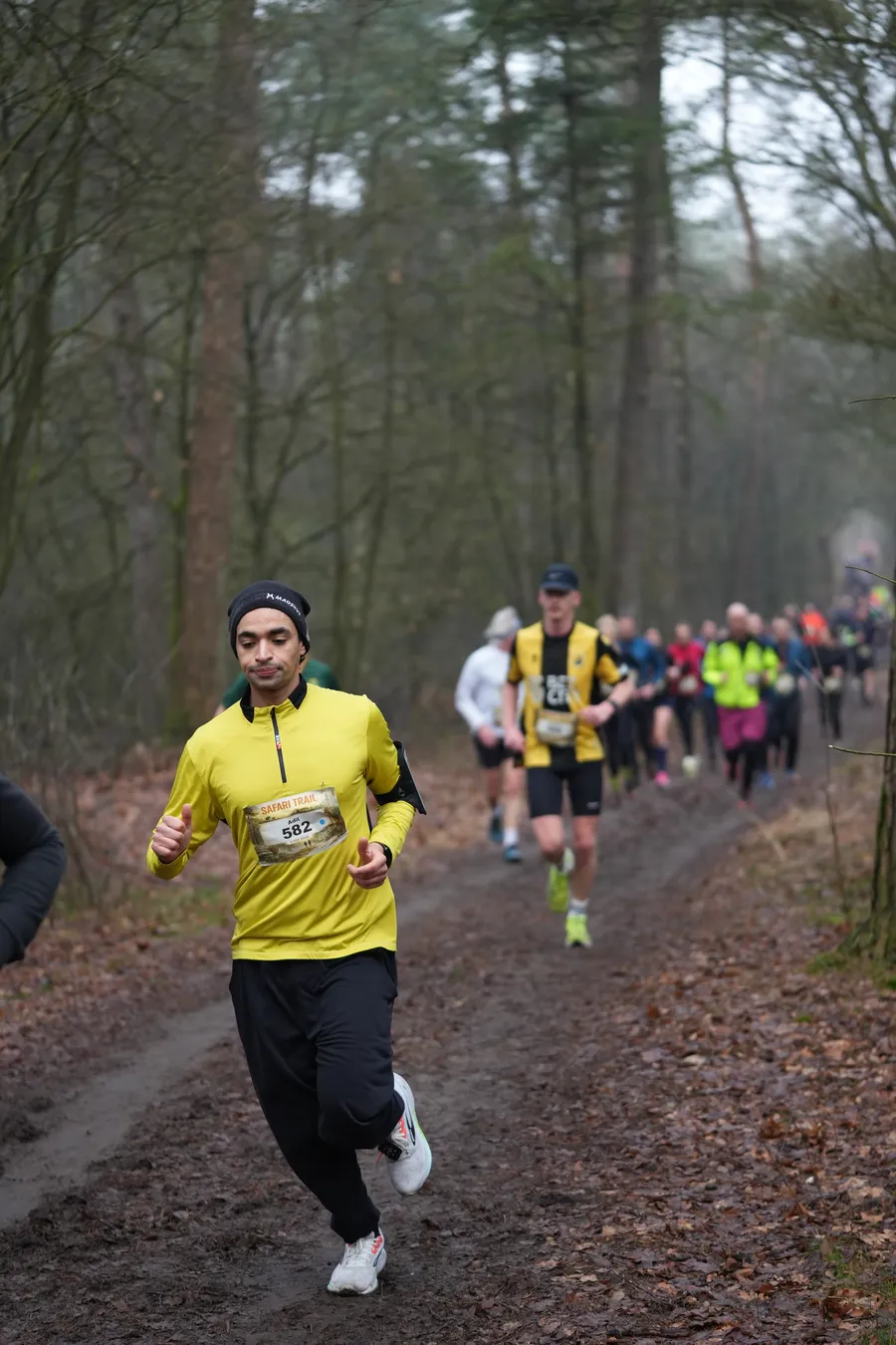 De kopgroep loopt door de mist het bos in